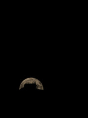 Silhouette of a church on top of a hill with the moon behind in the background.