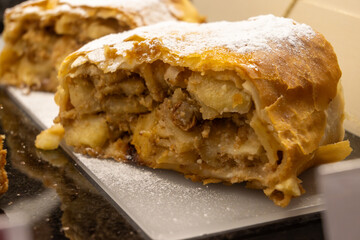 Austrian desserts, piece of apple strudel without whipped cream to be served in old traditional bakery cafe in Vienna, close up