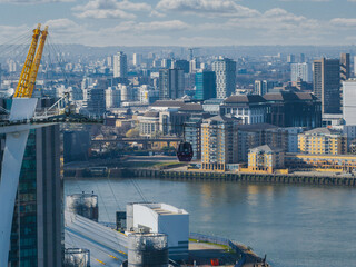 Aerial view of London with the O2 Arena, Emirates Air Line gondola over the River Thames, and modern buildings in Canary Wharf and Greenwich.