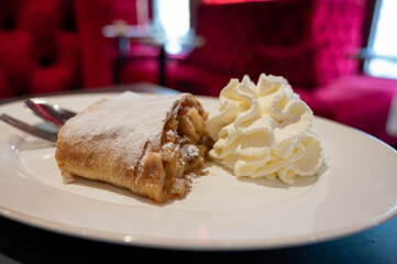 Austrian desserts, piece of apple strudel with whipped cream served in traditional bakery cafe in Vienna, close up