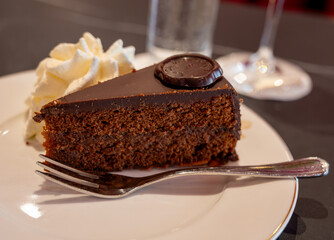 Piece of famous Sachertorte chocolate cake with apricot jam of Austrian origin served with whipped...