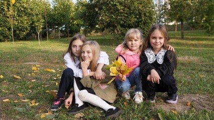 Fototapeta premium A joyful group of four happy children is posing together in a beautiful autumn setting surrounded by colorful leaves
