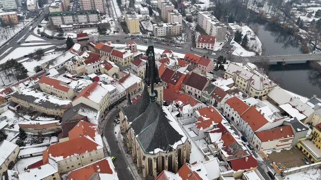 Aerial drone view of a picturesque Czech town with red rooftops and a grand snow-covered cathedral. Winter charm, historic architecture, and scenic beauty&mdash;perfect for travel or holiday themes.