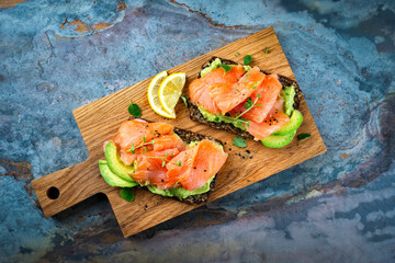 Pumpernickel bread sandwich snack with cured smoked salmon and fresh avocado served as close-up on...