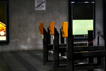 Ticket turnstiles with yellow card readers inside a subway station, emphasizing controlled access and public transportation infrastructure.

