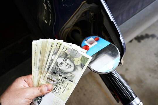 Car refueling with cash in hand&mdash;holding 2000 CZK bills. Everyday transaction, fueling up, and the simplicity of paying for fuel. Perfect for finance, daily life, or consumer behavior themes.