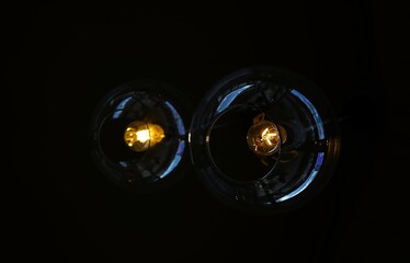 Two glass pendant light bulbs hanging from a dark ceiling, dimly lit interior.