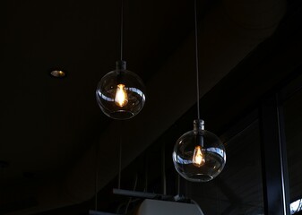Two glass pendant light bulbs hanging from a dark ceiling, dimly lit interior.