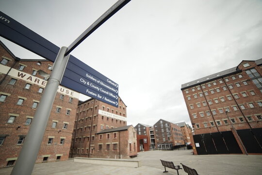 Directional Signpost Among Historic Warehouses at Gloucester Docks, England &ndash; Urban Heritage Scene with Brick Architecture and Overcast Sky