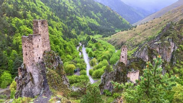The tower complex is located inside the green mountains. The Republic of Ingushetia, Russia. View of the defensive towers of Ingushetia in the North Caucasus on a cloudy day in spring. 4K