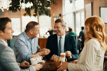 Group of business professionals laughing and networking at coffee shop meeting
