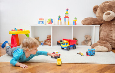 Sweet happy child boy having fun playing with colorful toys on the floor, at home