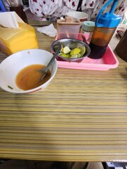 Empty bowl of spicy dipping sauce, limes, and condiments on a restaurant table.