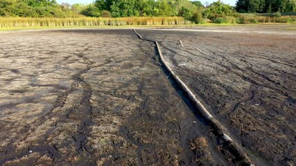 A dried-up lake from which. Drought at the bottom of the lake lie pipes.