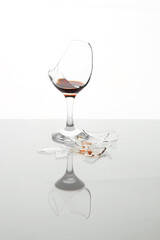 Pieces of broken glass with wine on table against white background