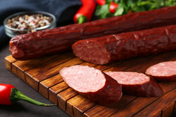 Delicious thin smoked sausage and spices on table, closeup
