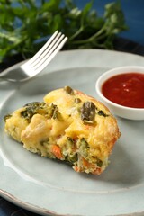 Piece of tasty vegetable casserole and sauce on blue table, closeup