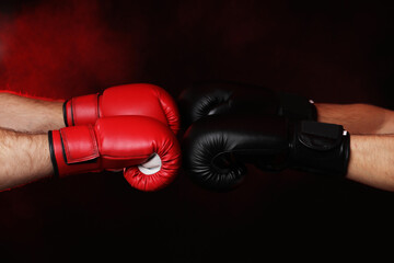 Men in boxing gloves fighting on dark background with smoke, closeup