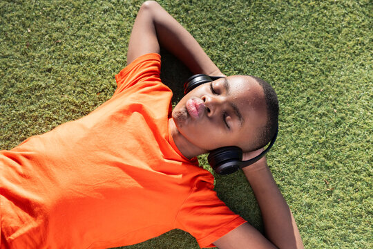 Listening to music, boy relaxing on grass with headphones, enjoying leisure time