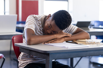 In school, student resting head on desk, feeling tired in classroom