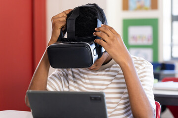 Using VR headset, student exploring virtual reality with tablet in school classroom