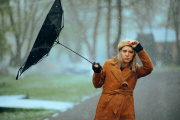 Woman with an Umbrella Broken by a Snowstorm. Unhappy person suffering in a bad stormy weather