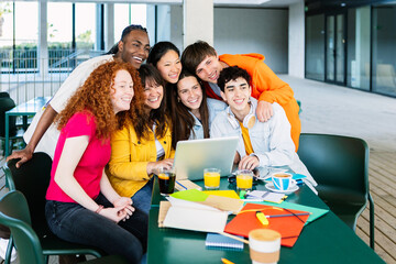 Portrait of young group of happy student friends standing together while studying on laptop. Youth and education lifestyle concept