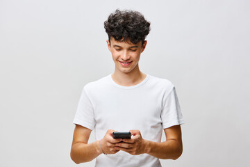 smiling young man using smartphone, casual attire, light background, modern communication,...