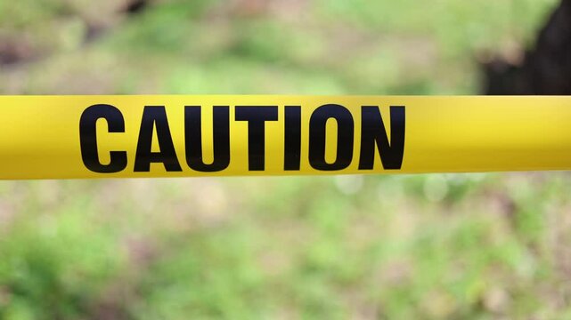 Yellow caution tape stretched across trees, blocking access to a restricted area, creating a sense of danger and warning
