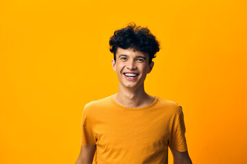 Young man smiling with curly hair on a vibrant yellow background, exuding joy and positivity His...