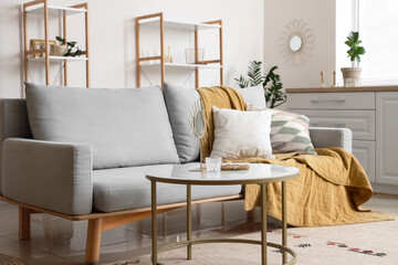 Interior of light living room with golden decor, table and sofa