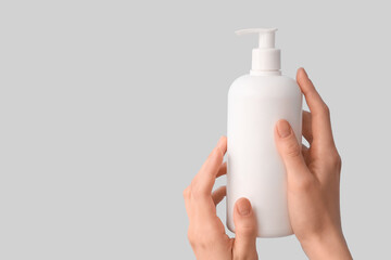 Female hands with bottle of natural cream on color background, closeup