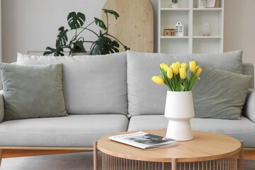 Stylish interior of living room with soft sofa and tulips