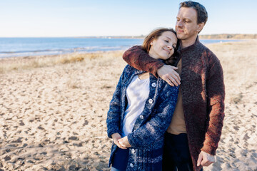 Loving couple walks on beach along sea on sunny autumn day. Weekend and lifestyle concept. High quality photo