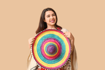 Beautiful young happy woman with sombrero on beige background. Cinco de Mayo celebration