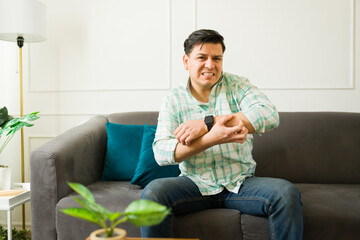 Uncomfortable latin man scratching irritated arm with rash, experiencing allergic reaction or...