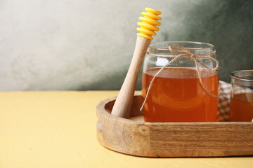 Jar of sweet honey with dipper on yellow table