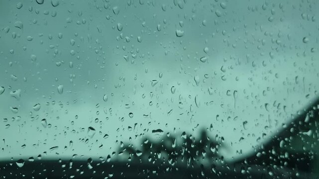 Water droplets on glass with a moody twilight sky beyond, ideal as a soft, atmospheric background for creative and storytelling projects