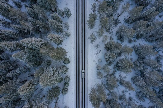 Aerial view of cars parked along a snow-covered road in a forest in Shingletown, California, USA. People are visiting the area for winter recreation. - Powered by Adobe