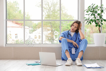 Tired female medical intern studying near window in clinic