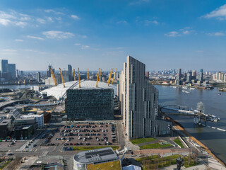 Aerial view of London with the O2 Arena's white dome and yellow supports, the River Thames, a...