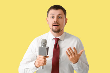 Male reporter with microphone on yellow background