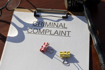 A criminal complaint paper secured in a clipboard and placed alongside a gavel on the judge’s...