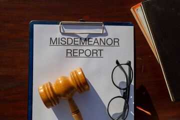 A document titled “Misdemeanor Report” secured in a clipboard and resting on the desk,...