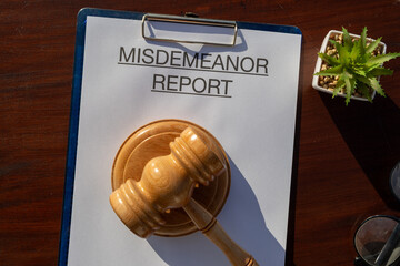 A document titled “Misdemeanor Report” secured in a clipboard and resting on the desk,...