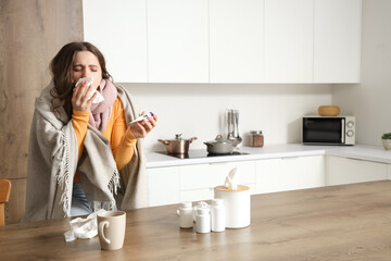 Ill young woman with thermometer and tissue sneezing in kitchen