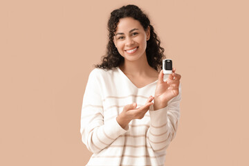 African-American woman with pulse oximeter on beige background