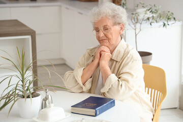 Fototapeta premium Senior woman with Bible praying at home