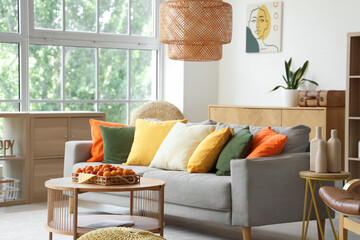 Comfortable sofa and tray with apricots on coffee table in interior of living room