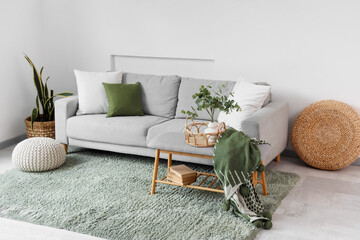Interior of light living room with grey sofa, soft bench and poufs